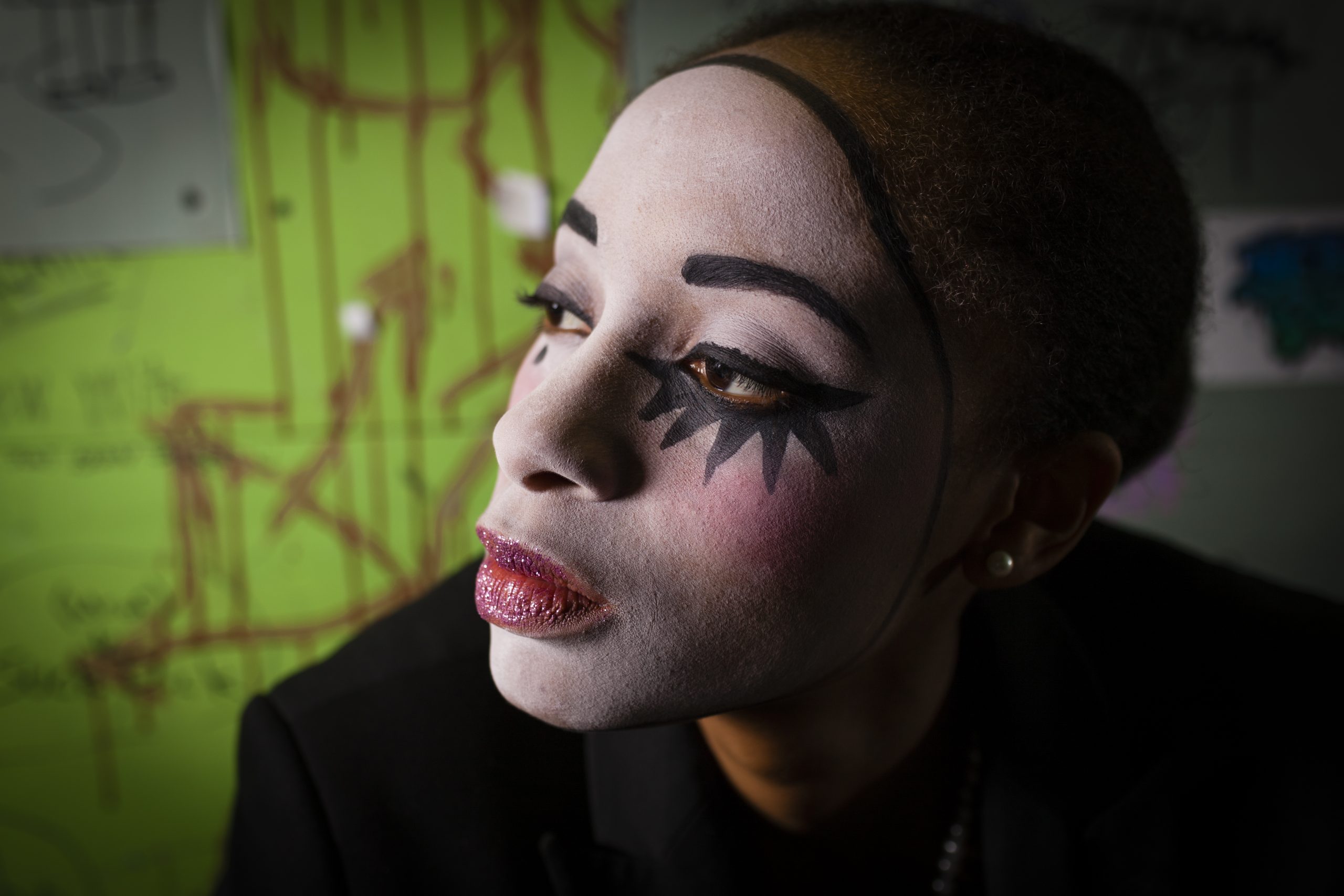 Portrait of young woman with face painted as pierrot